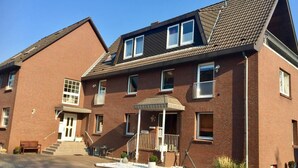 A two-story brick building with a front porch, a staircase, and a small garden area. - House Nicole vacation apartment 5 (Cuxhaven)