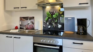 Une cuisine moderne avec des armoires blanches, une hotte de cuisinière en acier inoxydable, une machine à café et un évier.