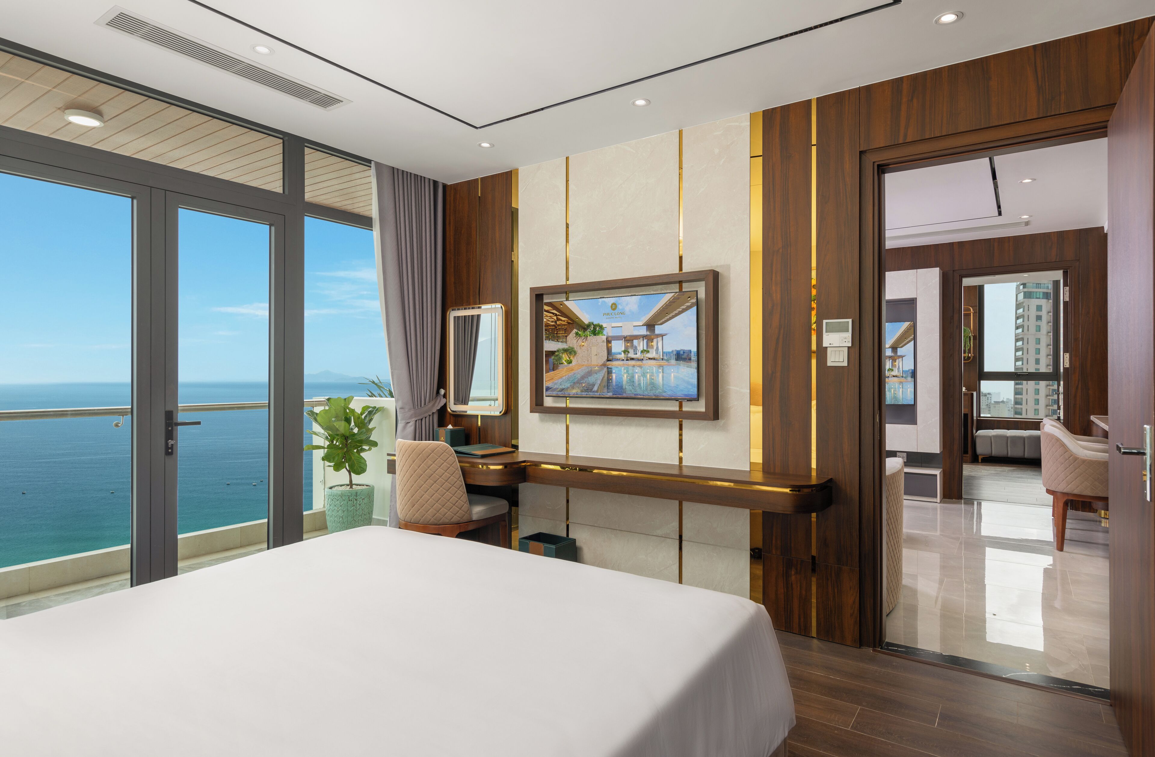 Een moderne hotelkamer met een groot bed, een bureau en uitzicht op zee.