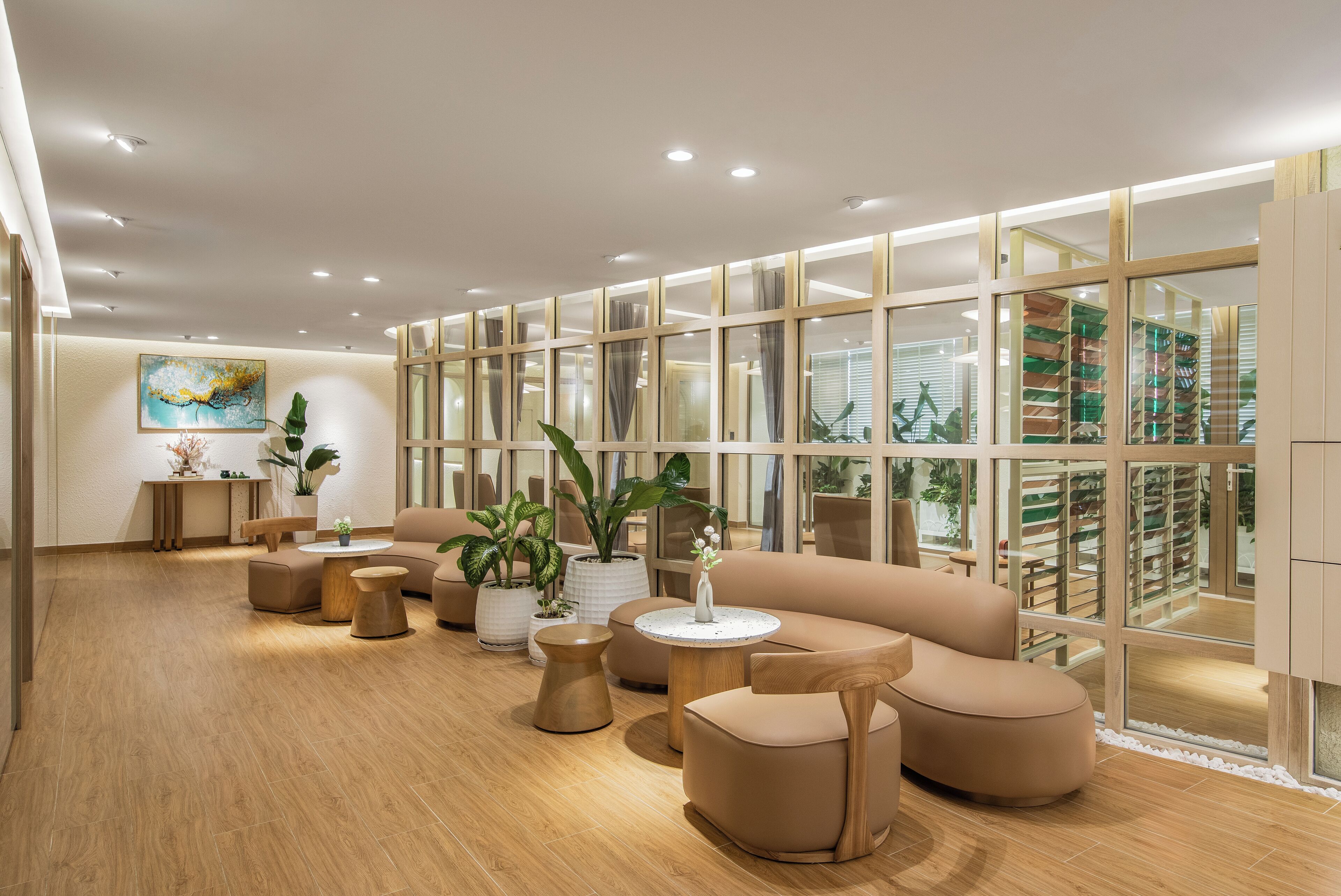 A modern lounge area with sofas, round tables, and potted plants.
