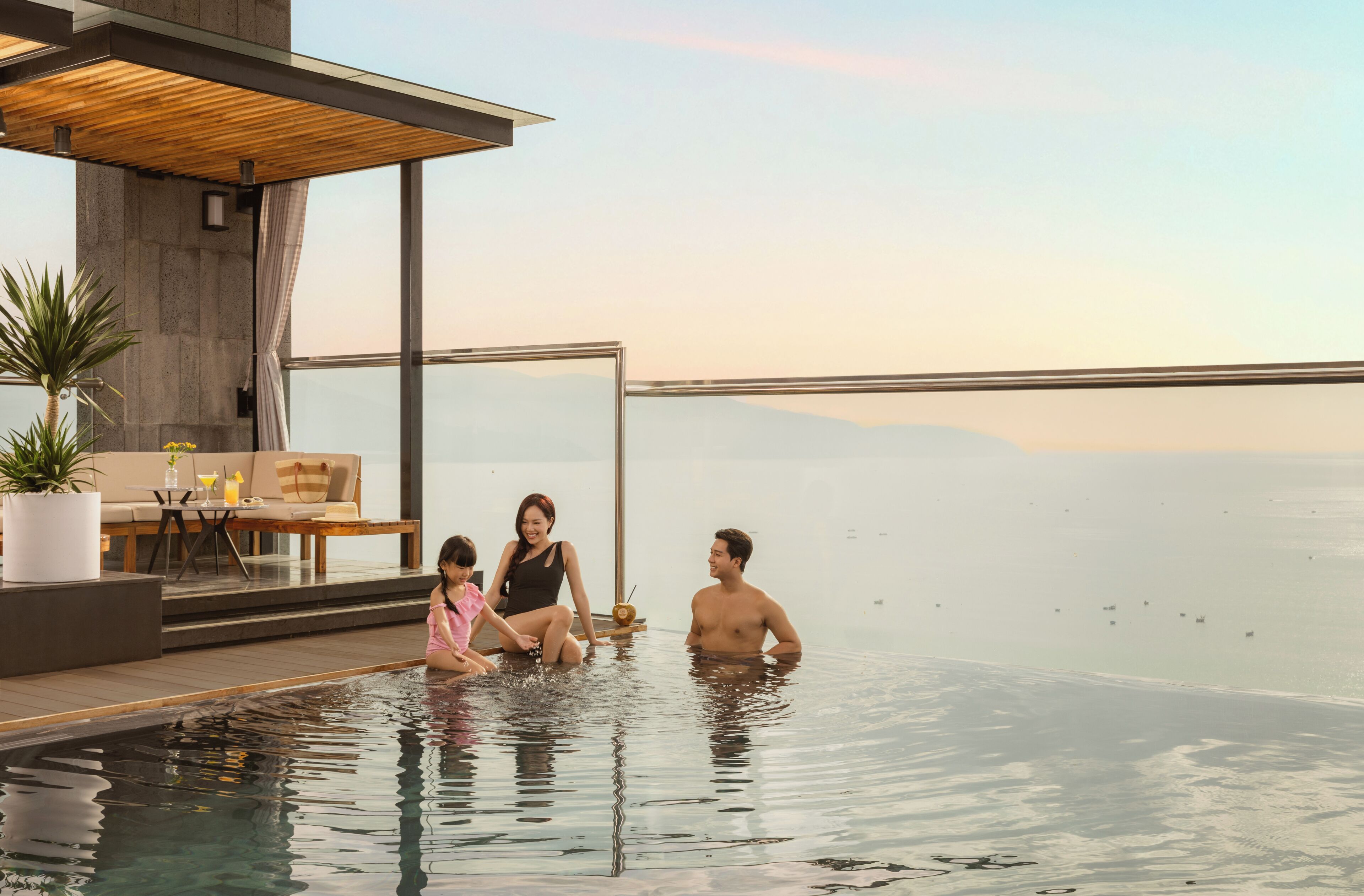 A modern infinity pool with a clear view of the sea and mountains in the background.