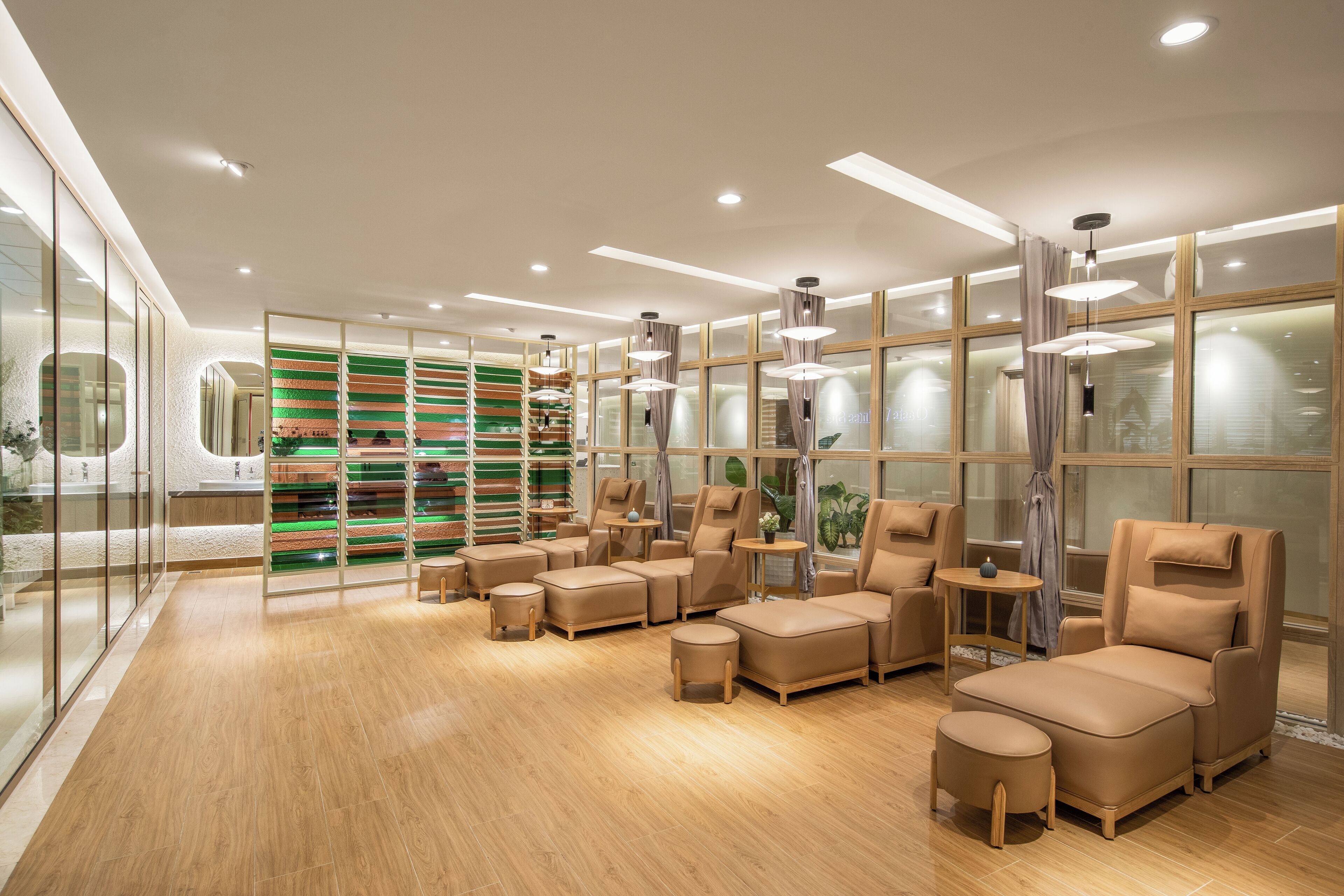 A modern spa room with leather seating, a glass wall, and a green-striped wall.