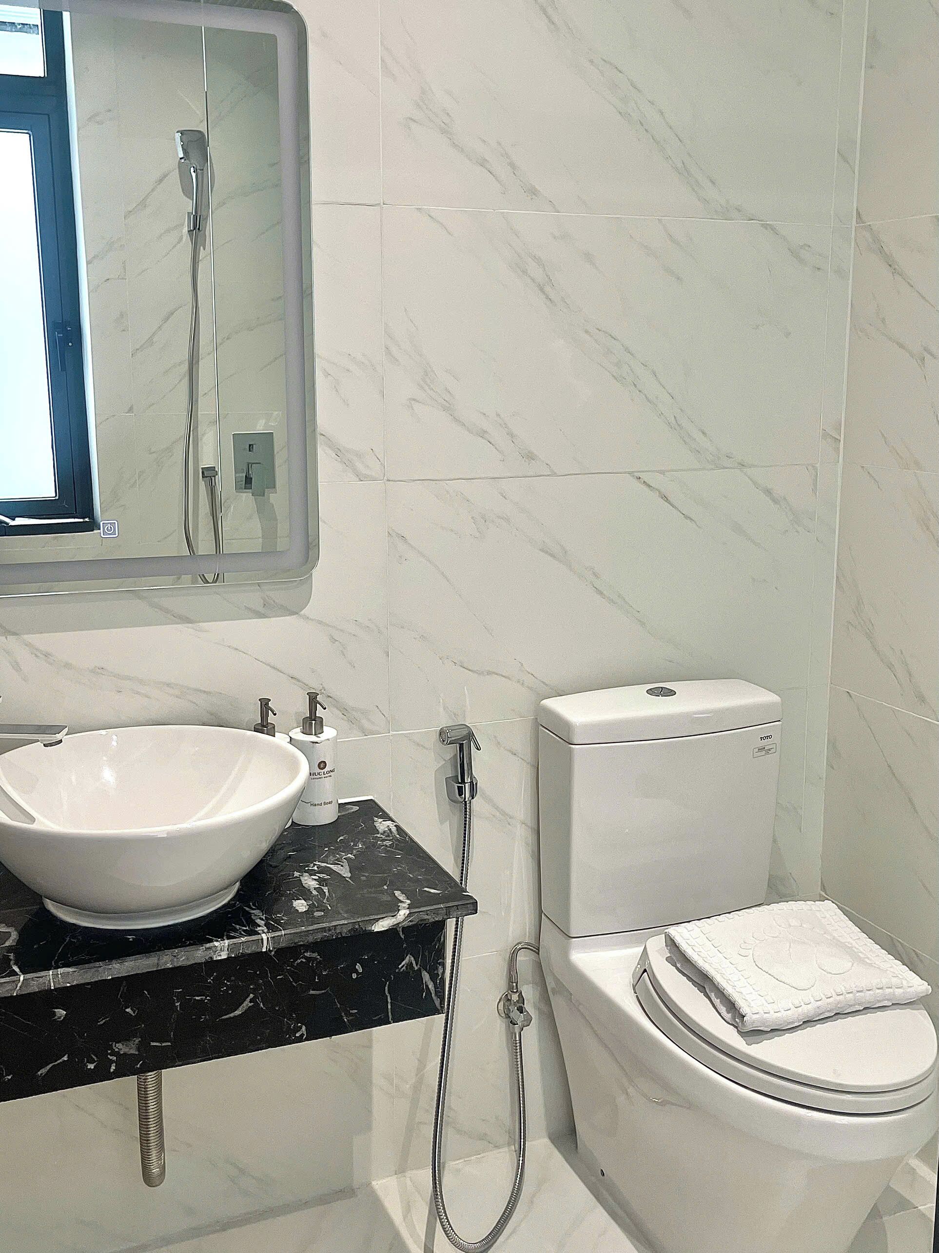 A bathroom with a white sink, a mirror, a toilet, and a shower.