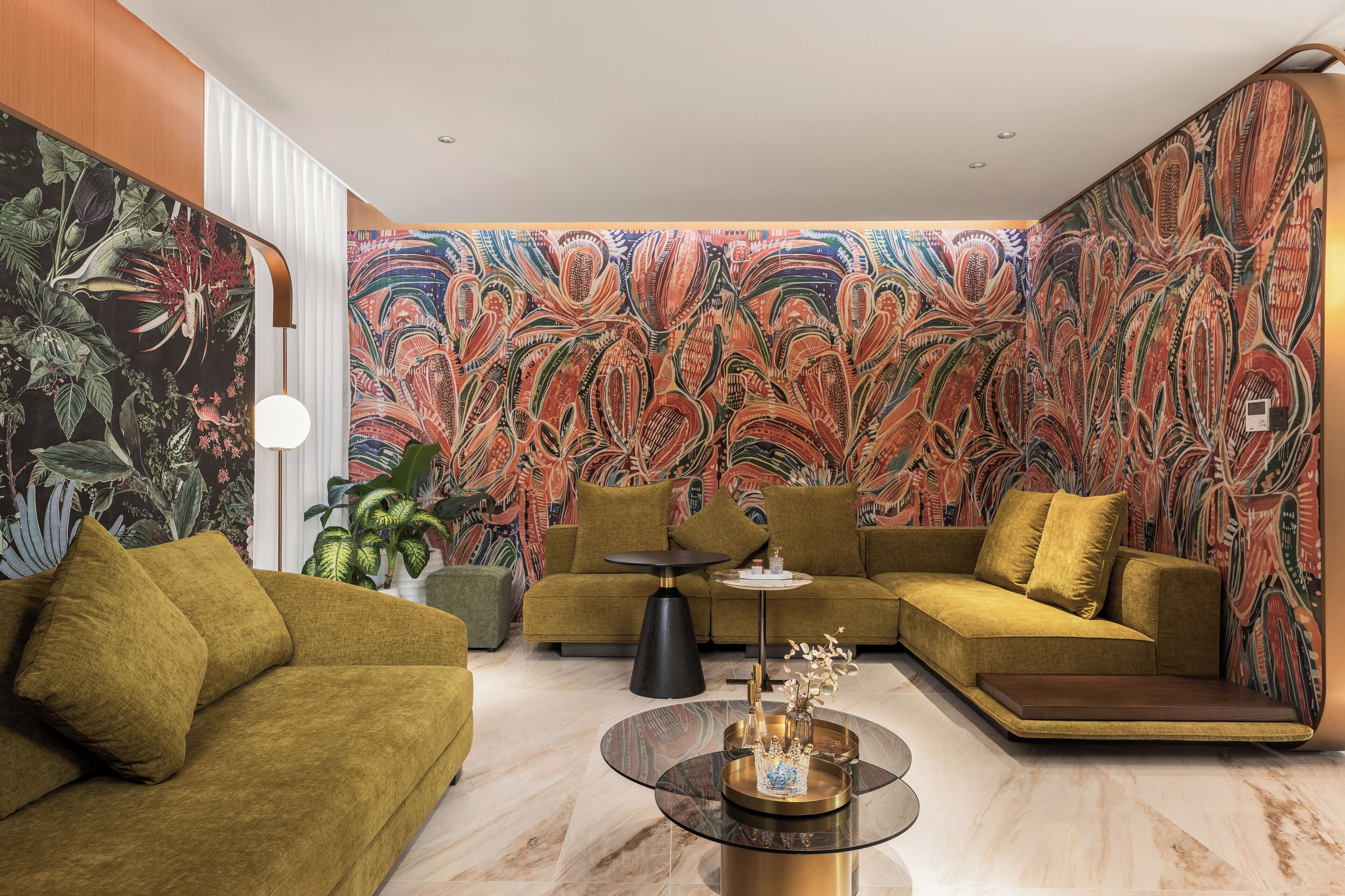 A modern living room with a green sofa, a round coffee table, and a vibrant floral mural on the walls.