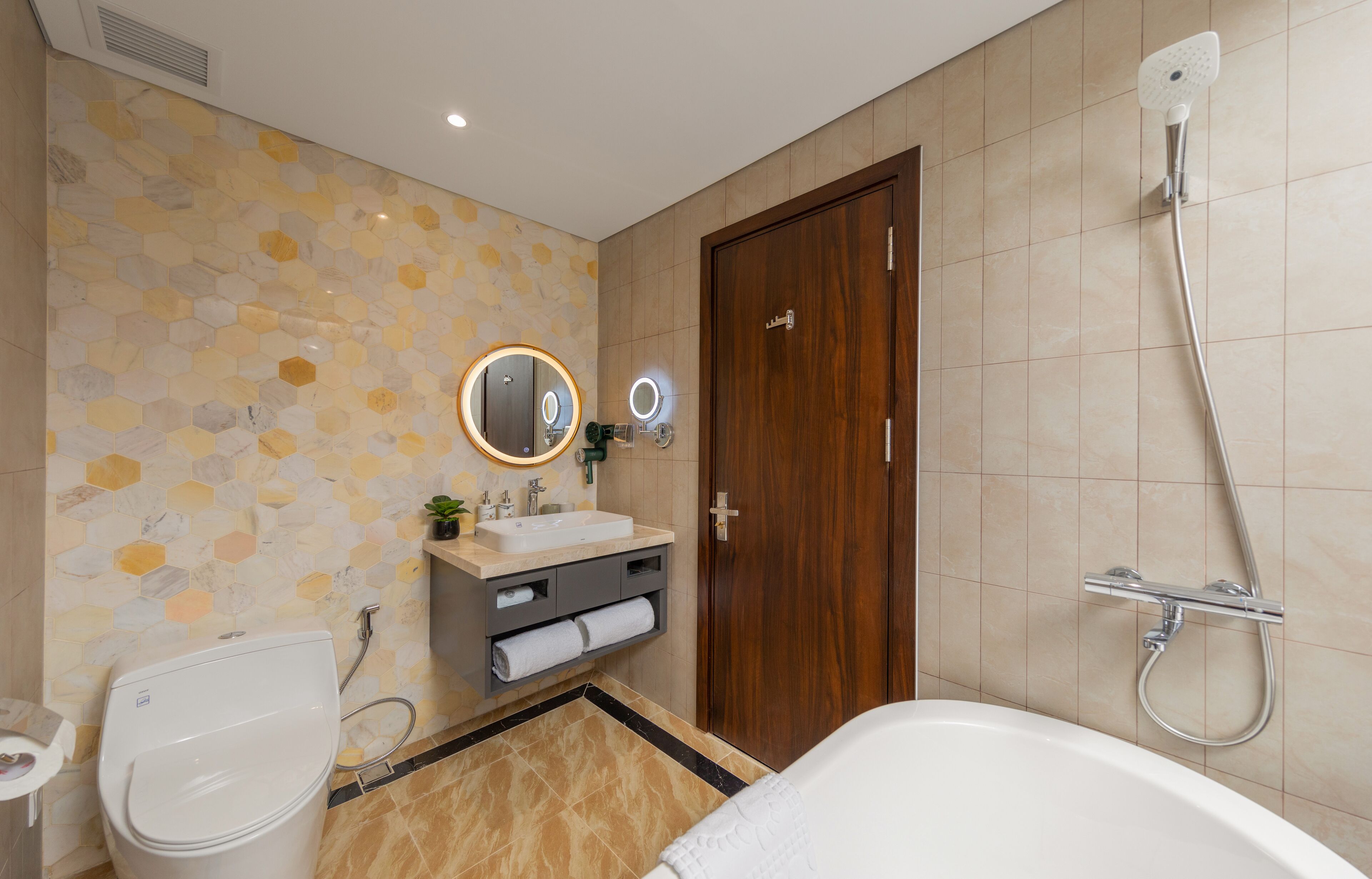 Een badkamer met toilet, wastafel, spiegel, douche en een houten deur.
