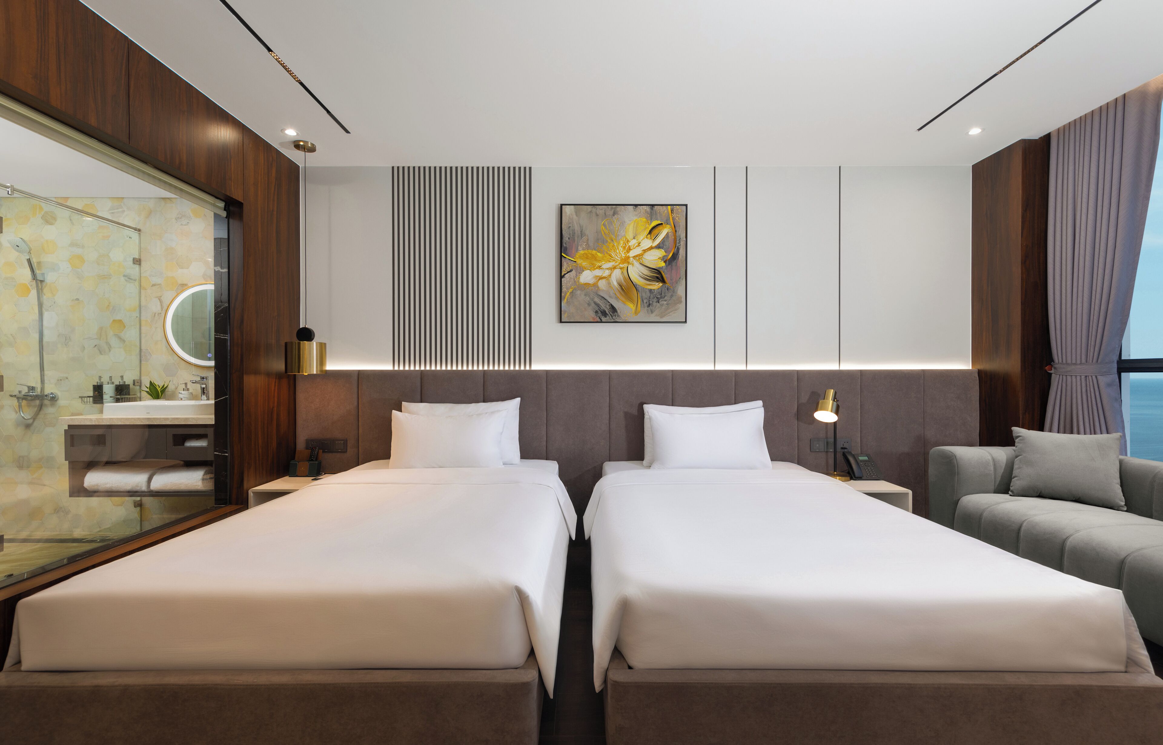 A modern hotel room with two beds, a sofa, a large mirror, and a painting on the wall.