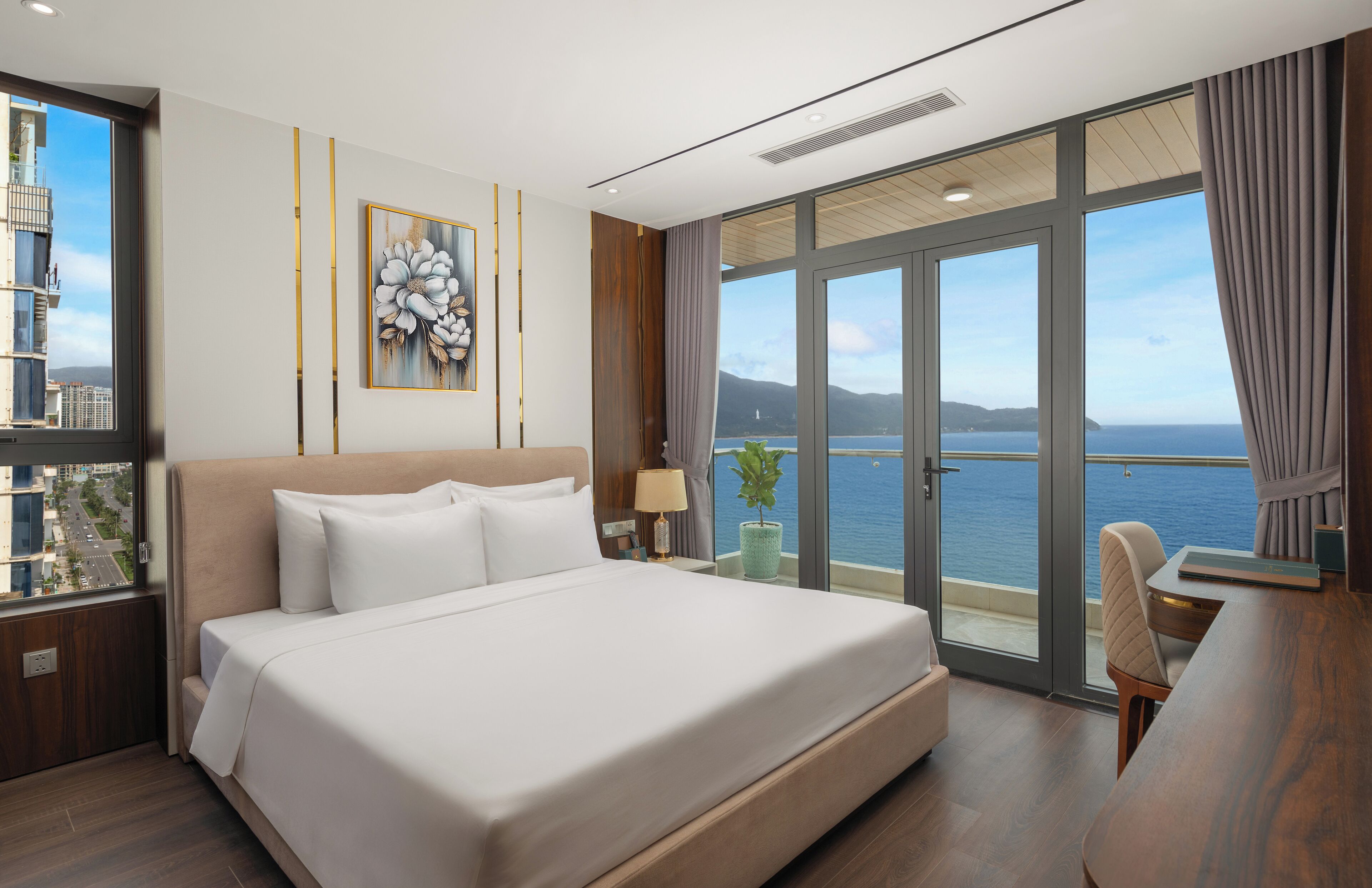 Habitació d'hotel moderna amb un llit gran, un escriptori i vista al mar.