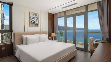 Habitació d'hotel moderna amb un llit gran, un escriptori i vista al mar.