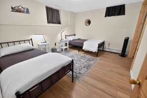 Une chambre avec deux lits, un bureau, une chaise, un tapis et une horloge murale.