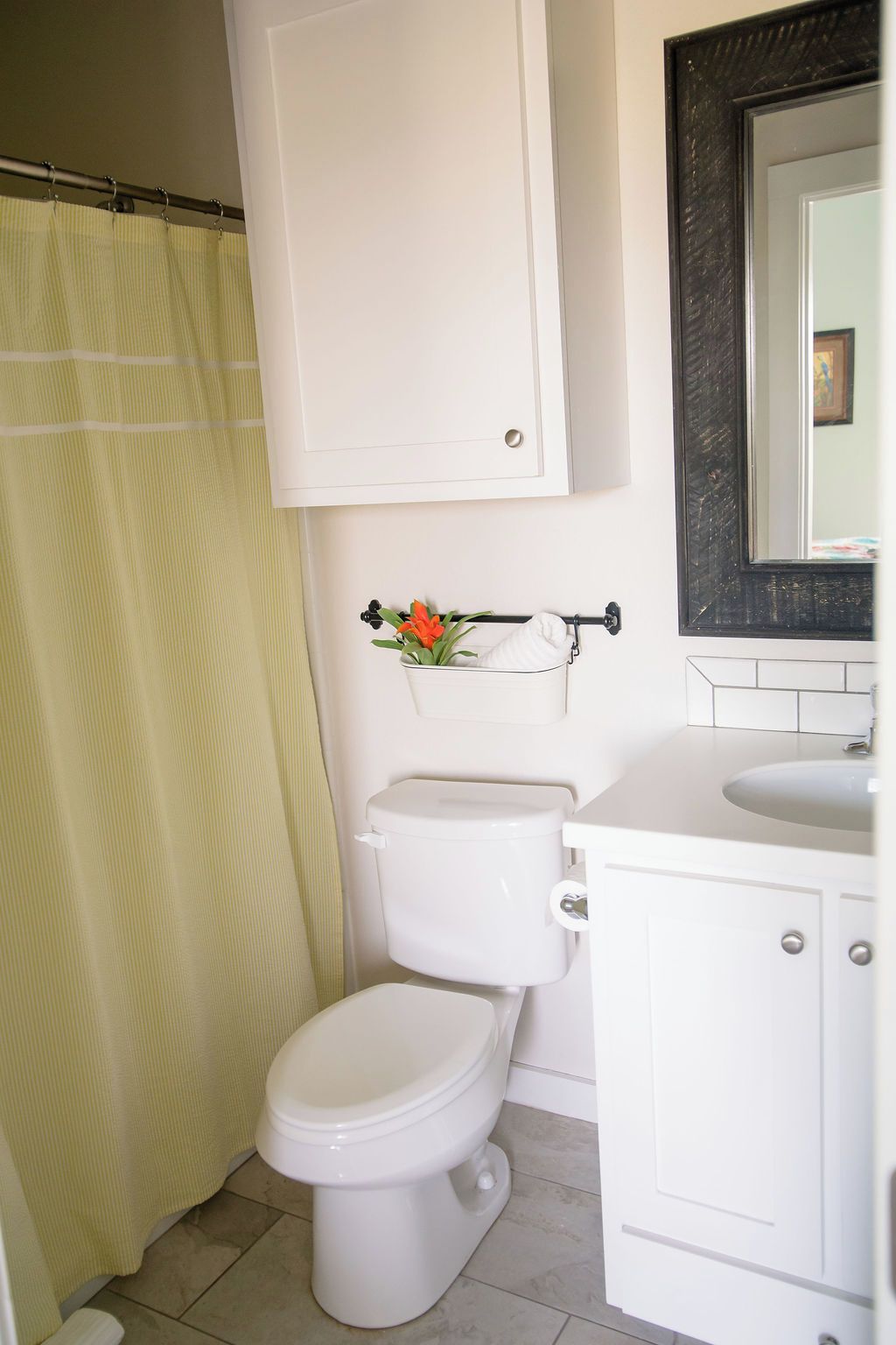 A bathroom with a toilet, a sink, a mirror, and a shower curtain.
