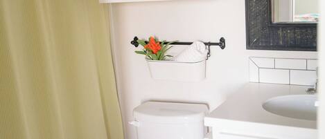A bathroom with a toilet, a sink, a mirror, and a shower curtain.