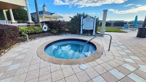 A swimming pool with a tiled deck, a metal ladder, and a signboard.