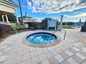 A swimming pool with a tiled deck, a metal ladder, and a signboard. - 1 Min to Disney! Resort Condo w/Pool & Wifi (Kissimmee)