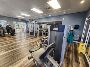 Une salle de sport équipée de matériel d’exercice, dotée d’un plancher en bois et d’un mur bleu.