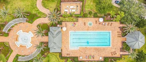 Vista aérea de un resort con piscina, áreas de descanso y jardines ajardinados.