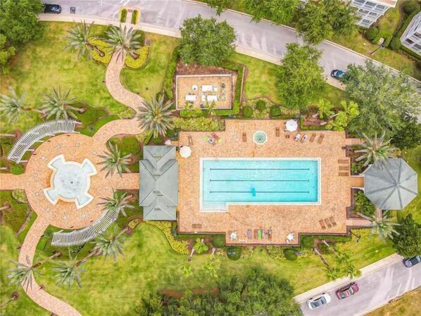 An aerial view of a resort with a swimming pool, lounge areas, and landscaped gardens.