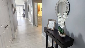 A hallway with a dark console table, a framed welcome sign, and a decorative mirror.