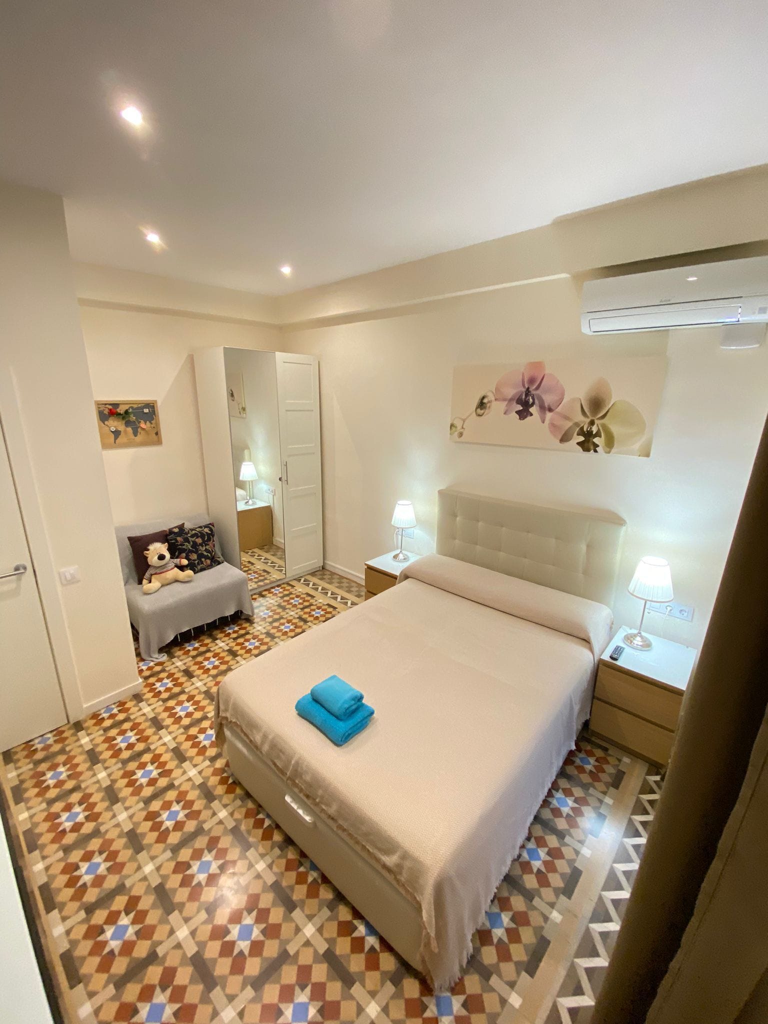 Ein Schlafzimmer mit Bett, Nachttisch, Kommode, Spiegel und einer Karte an der Wand.
