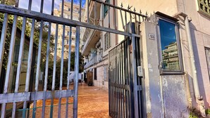 Un cancello conduce a un edificio con rivestimento in piastrelle e un balcone.