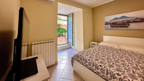Una camera da letto con un letto, un termosifone, una TV e un quadro raffigurante una barca sull'acqua.