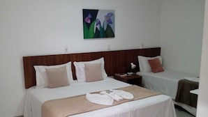 A hotel room with a large bed, a bedside table, a nightstand, and a wall-mounted painting. - Pousada Oca (Holambra)