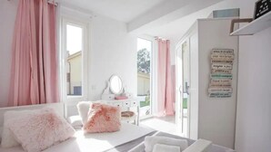 Un dormitorio con cama, almohadas mullidas, cómoda, espejo y puerta que da a un balcón.