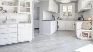 Una cocina moderna con armarios blancos, una isla central y una ventana sobre el fregadero.