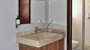 A bathroom with a beige marble sink, a wooden cabinet, a mirror, and a glass shower enclosure. - Beautiful Department in the Historic Center. 201 (San Luis Potosí)