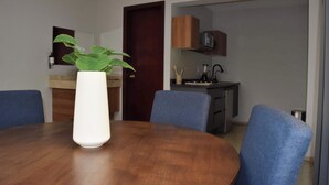 A dining area with a round wooden table, blue chairs, and a white vase with a plant. - Beautiful Department in the Historic Center. 201 (San Luis Potosí)