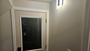 A closed door with a window, a light switch, and a doorbell on the wall. - Welcoming Private 2 Bedroom Suite (Winnipeg)