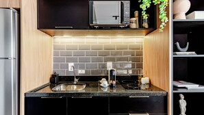 Une cuisine moderne avec des meubles de couleur noire, un réfrigérateur en acier inoxydable, un four à micro-ondes et un évier.