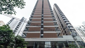 Un immeuble de grande hauteur doté d’une architecture moderne, caractérisé par une grille de fenêtres et une façade ornée de lambris en bois verticaux.