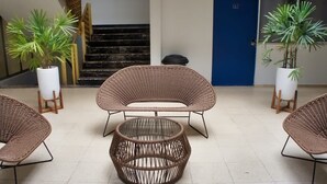 Un vestíbulo con mobiliario de mimbre, una escalera y plantas en macetas.