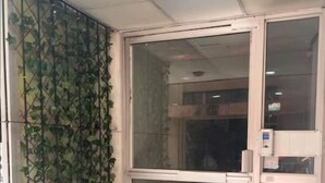 Una entrada de edificio con puerta de vidrio y portón metálico.