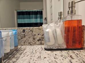 A bathroom counter with a soap dispenser, a bottle of liquid soap, and a container holding cotton swabs. - The Restful Refuge Unwind in Comfort and Peaceful Serenity (Madison)