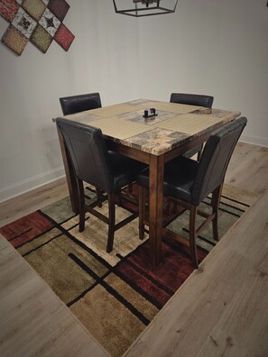 A dining table with a woven table runner, four chairs, and a small table lamp. - The Restful Refuge Unwind in Comfort and Peaceful Serenity (Madison)