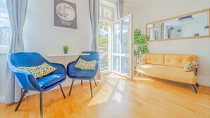 A modern living room with a blue chair, a yellow sofa, and a large window with curtains.