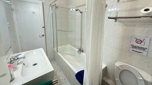 Et stilfuldt badeværelse med bruseniche, hvid vask og toilet.