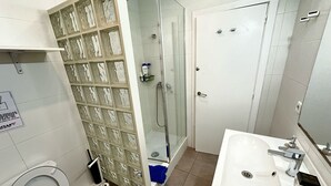 Et badeværelse med toilet, vask og bruseområde.