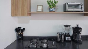 Una cucina con piano cottura a gas, tostapane, frullatore e macchina da caffè.