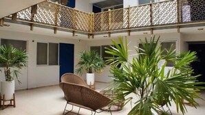 Un ambiente interno spazioso, con soffitto alto, ringhiera in legno decorativa e diverse piante in vaso.