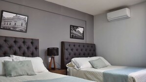 Una camera d'albergo con due letti, un climatizzatore a parete e due quadri appesi.