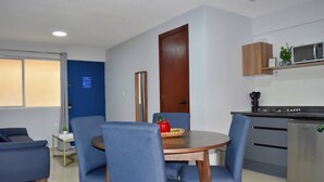 Una cucina moderna con forno a microonde, lavello e pensili. C'è un'area pranzo con un tavolo rotondo e sedie blu.