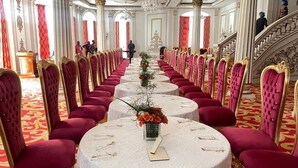 A long dining table with red upholstered chairs, a chandelier, and a staircase. - CHATEAU LE MARARA (Bwishyura)