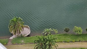 A circular wooden dock by a calm lake, surrounded by lush greenery and palm trees. - CHATEAU LE MARARA (Bwishyura)