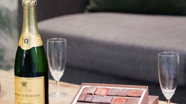 A bottle of champagne, a box of chocolates, and two glasses on a wooden table. - Besta 189 - Superb cozy apartment (Asnières-sur-Seine)