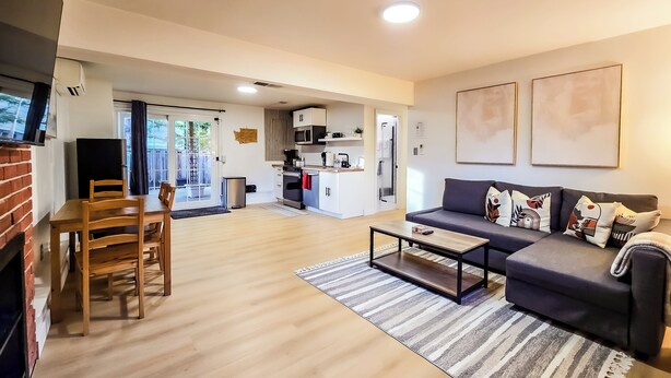 A modern living room with a sofa, coffee table, and dining area. - Private guest suite with Full kitchen & laundry (Kirkland)