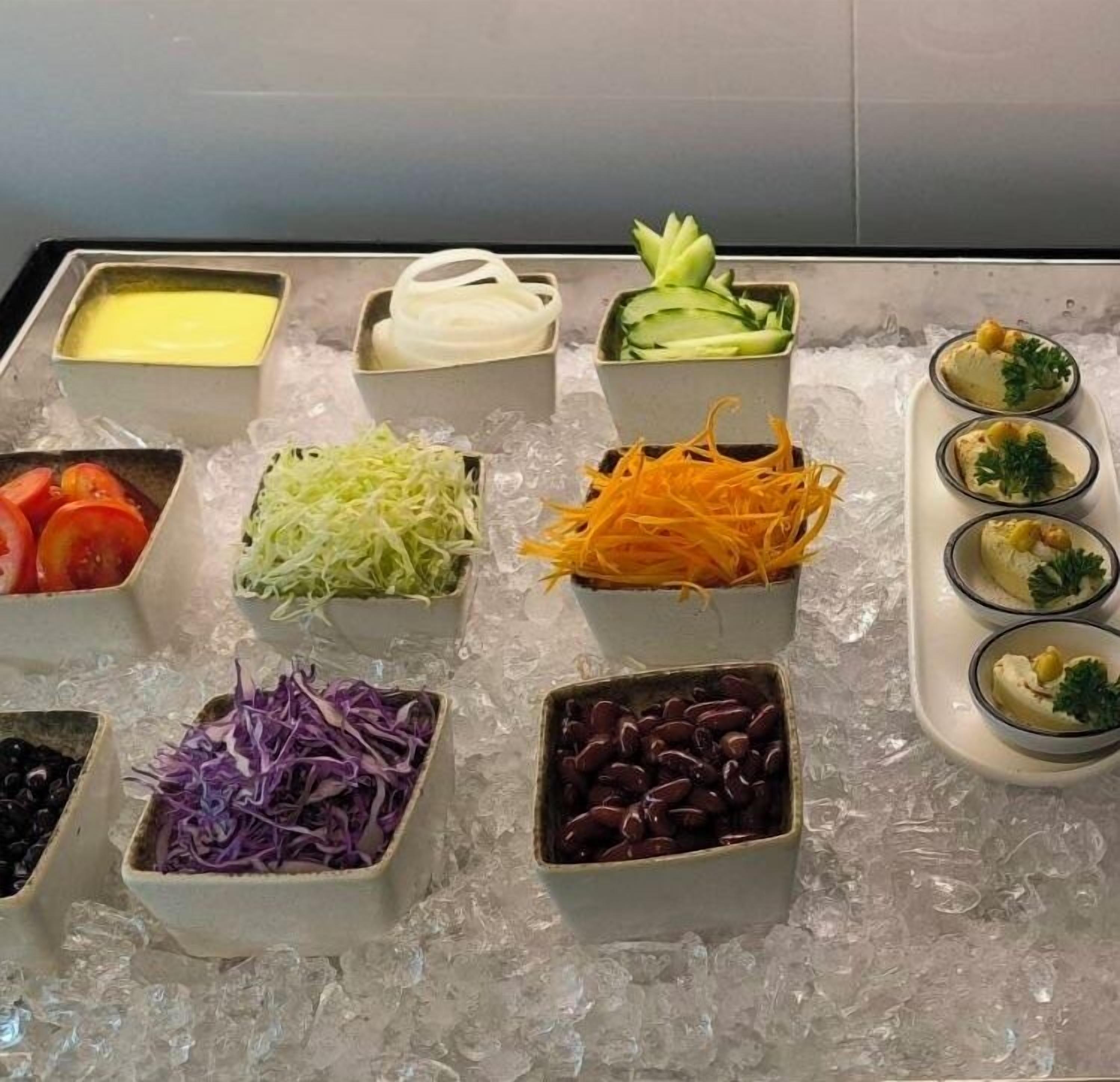 A variety of food items, including sliced vegetables and beans, arranged on a tray of ice.