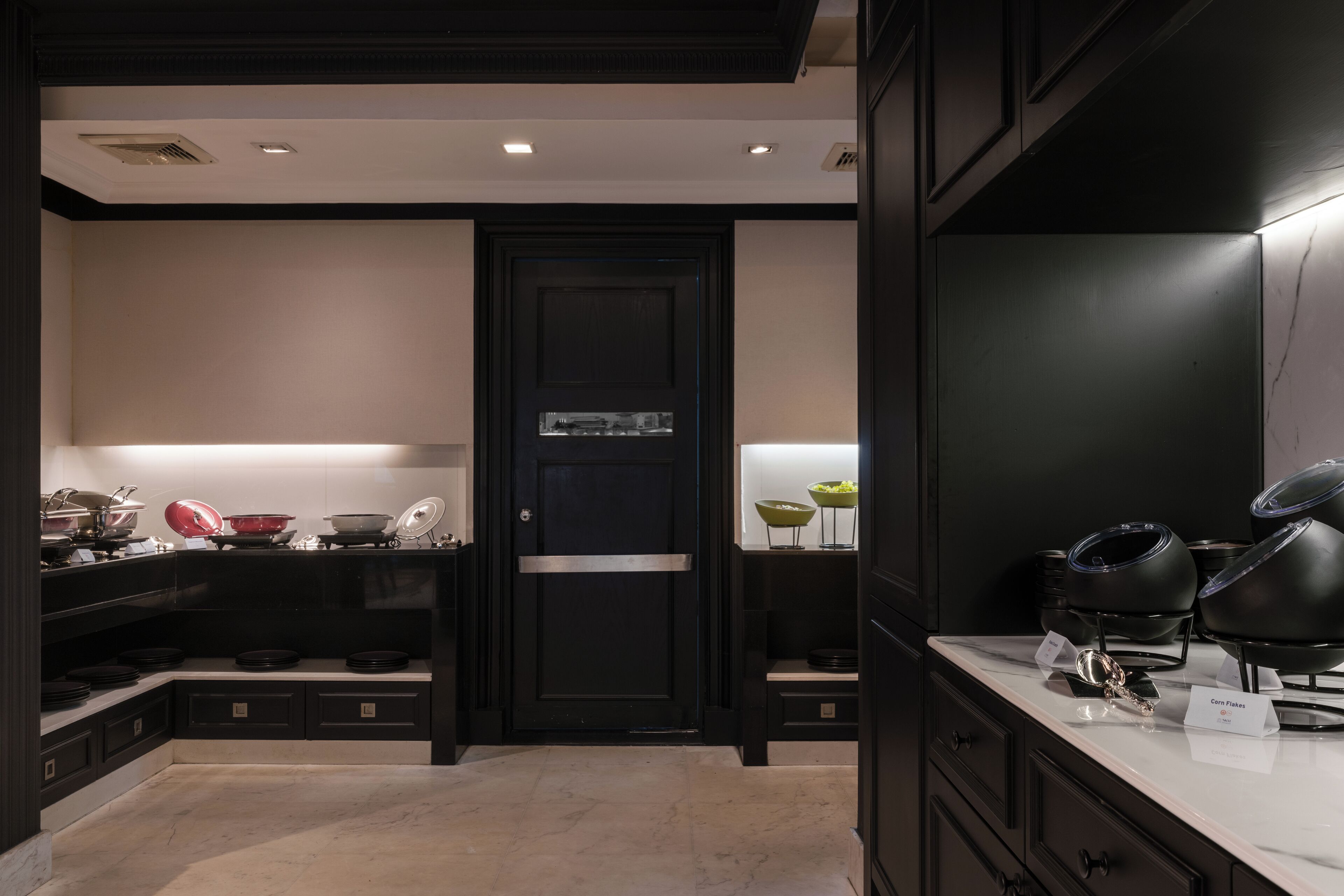 Una cocina moderna con armarios negros, encimera de mármol y una puerta negra con un pequeño ventanal.