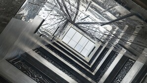 Una escalera de caracol con ventanal central de vidrio, barandales metálicos y un diseño arquitectónico moderno.